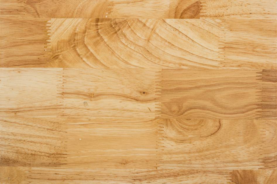 Close-up of hands applying wood glue to a dovetail joint with clamps nearby