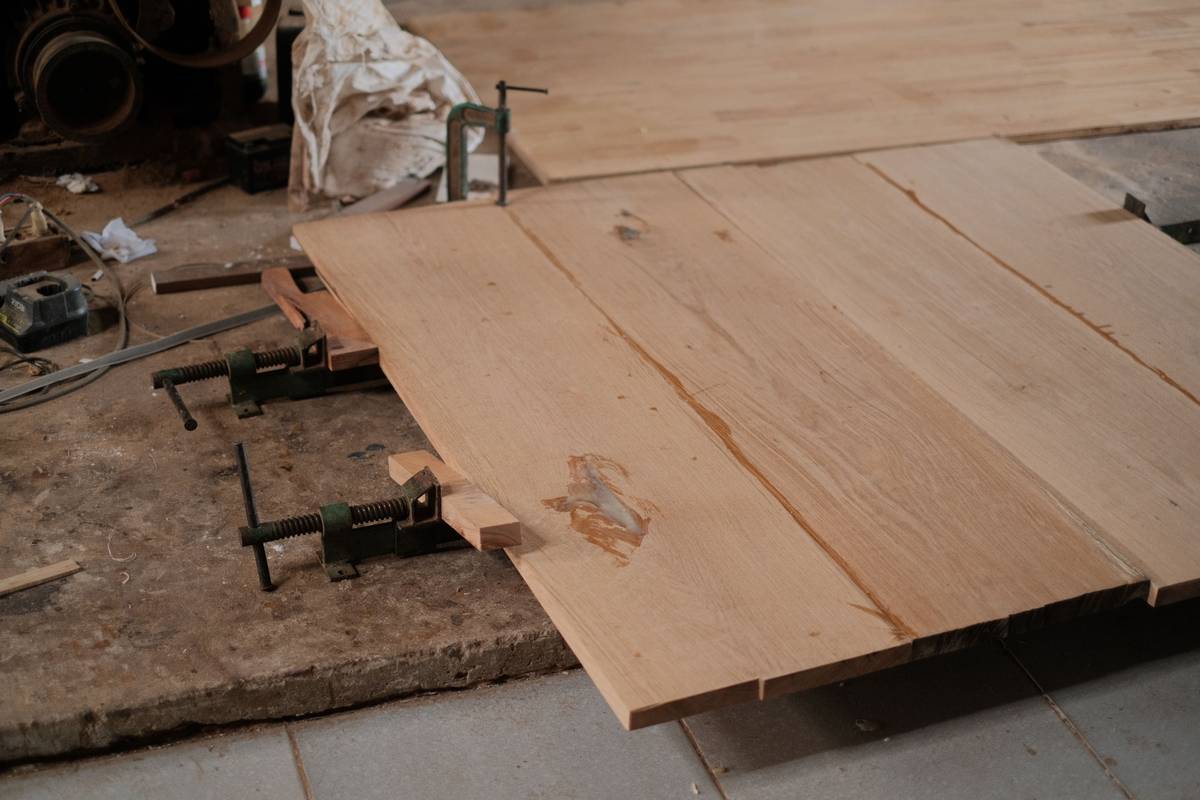 Close-up of hands applying wood glue for woodworking on pine boards with brush