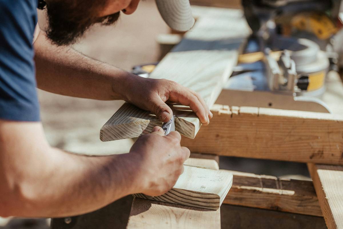 Close-up of hands applying diy project wood glue what are on oak wood pieces with clamps nearby