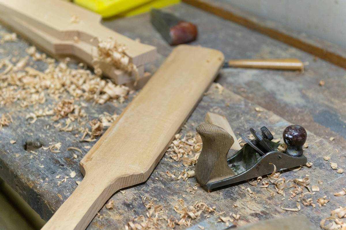 Close-up of a woodworking glue scraper removing excess glue from a wooden joint