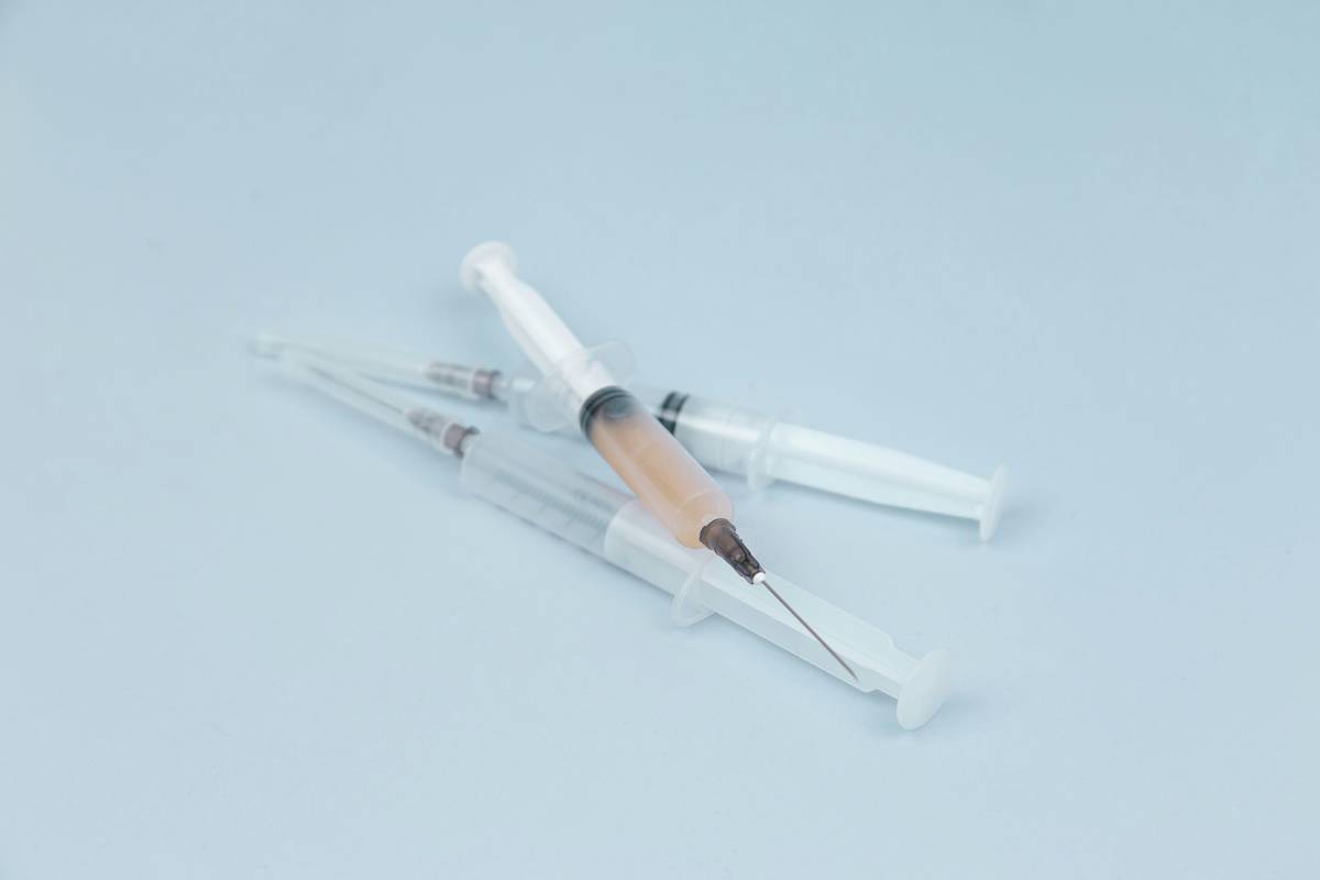 Close-up of woodworking glue syringe dispensing precise bead of glue into corner joint