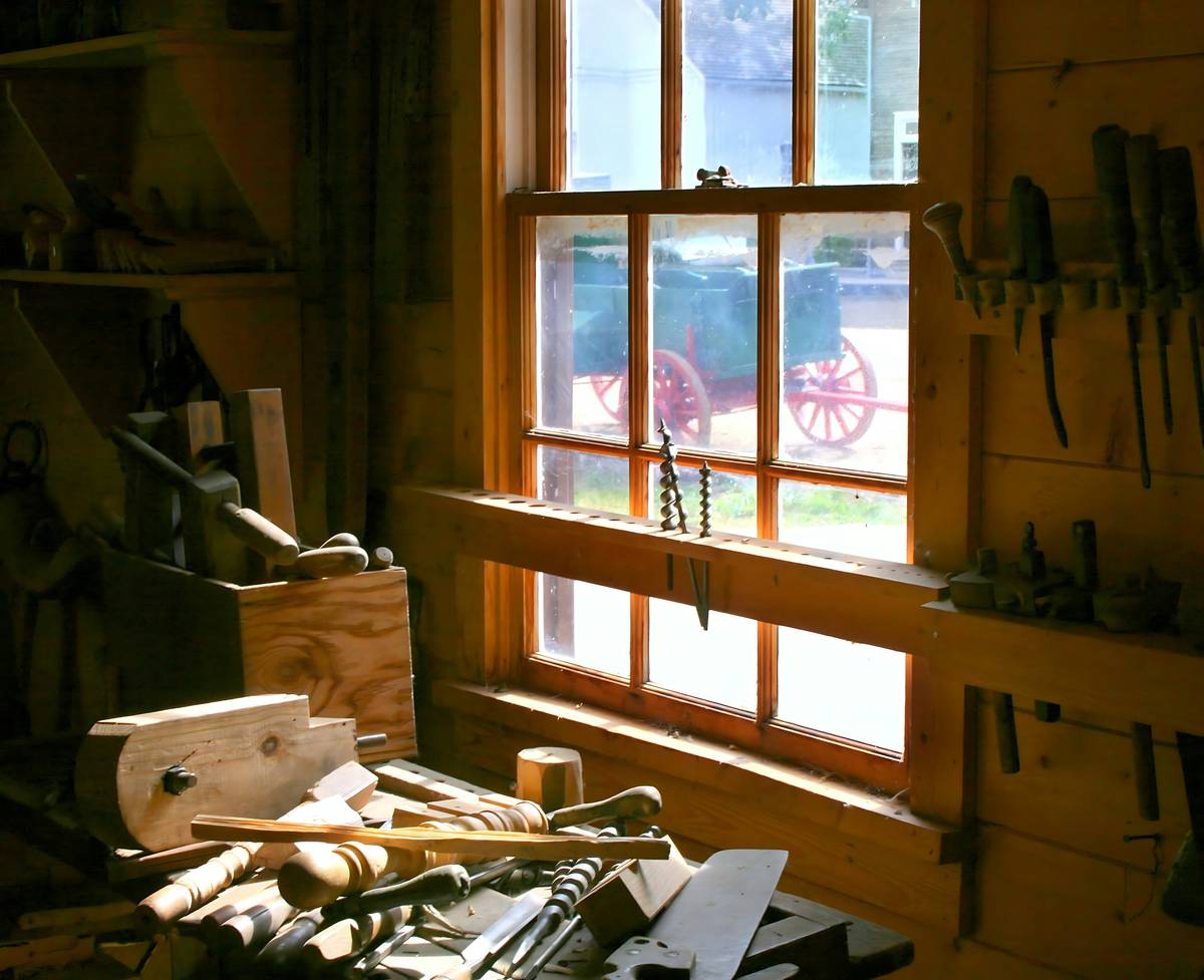 Close-up of two oak boards bonded with high strength wood glue, clamped under professional bar clamps on a workbench
